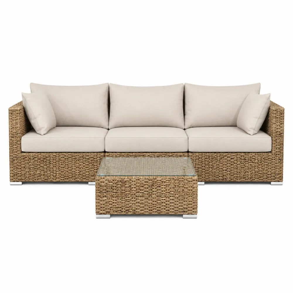 Sofa i stolik z rattanu i szkła z beżowymi poduszkami
